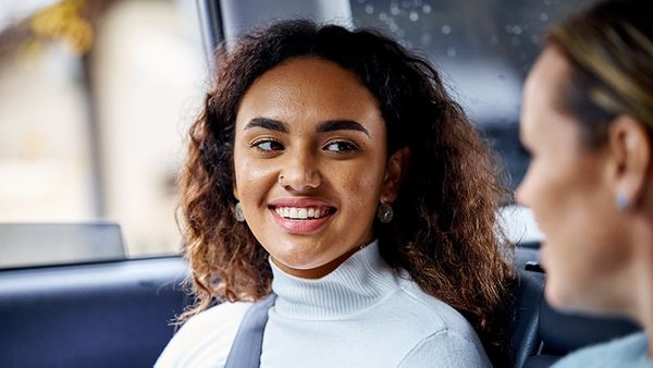 girl with curly hair smiling at her mum in car.jpg